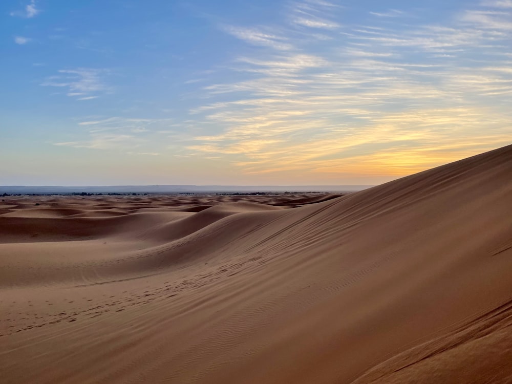 the sun is setting over the sand dunes