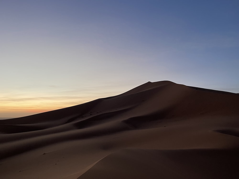 the sun is setting over the sand dunes