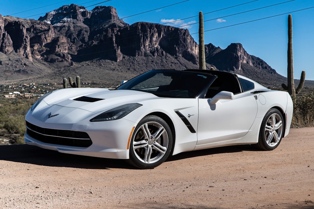 a white sports car parked in front of a mountain