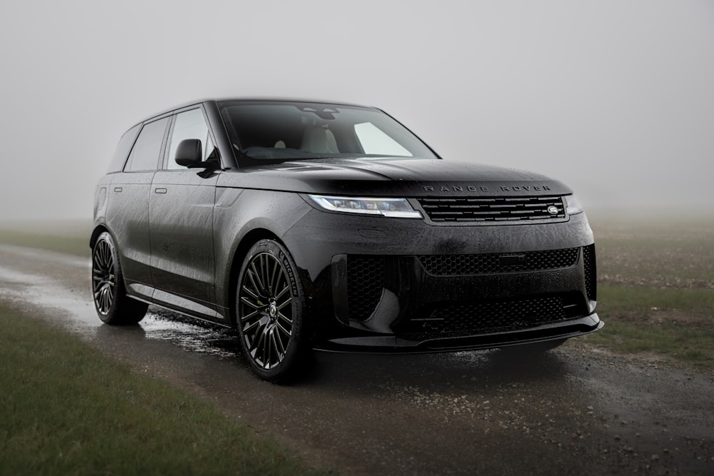 a black range rover driving on a wet road