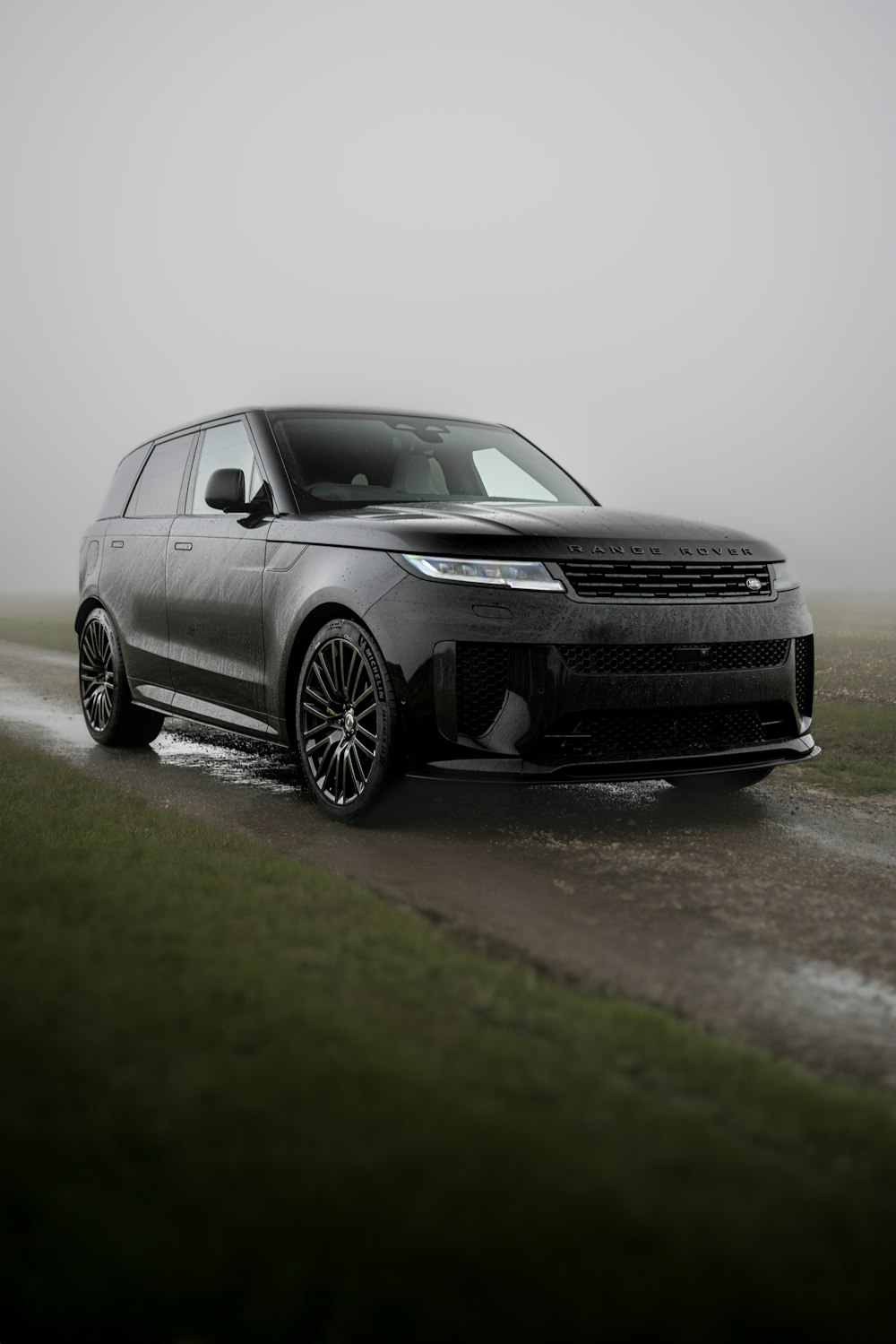 a black range rover driving on a wet road