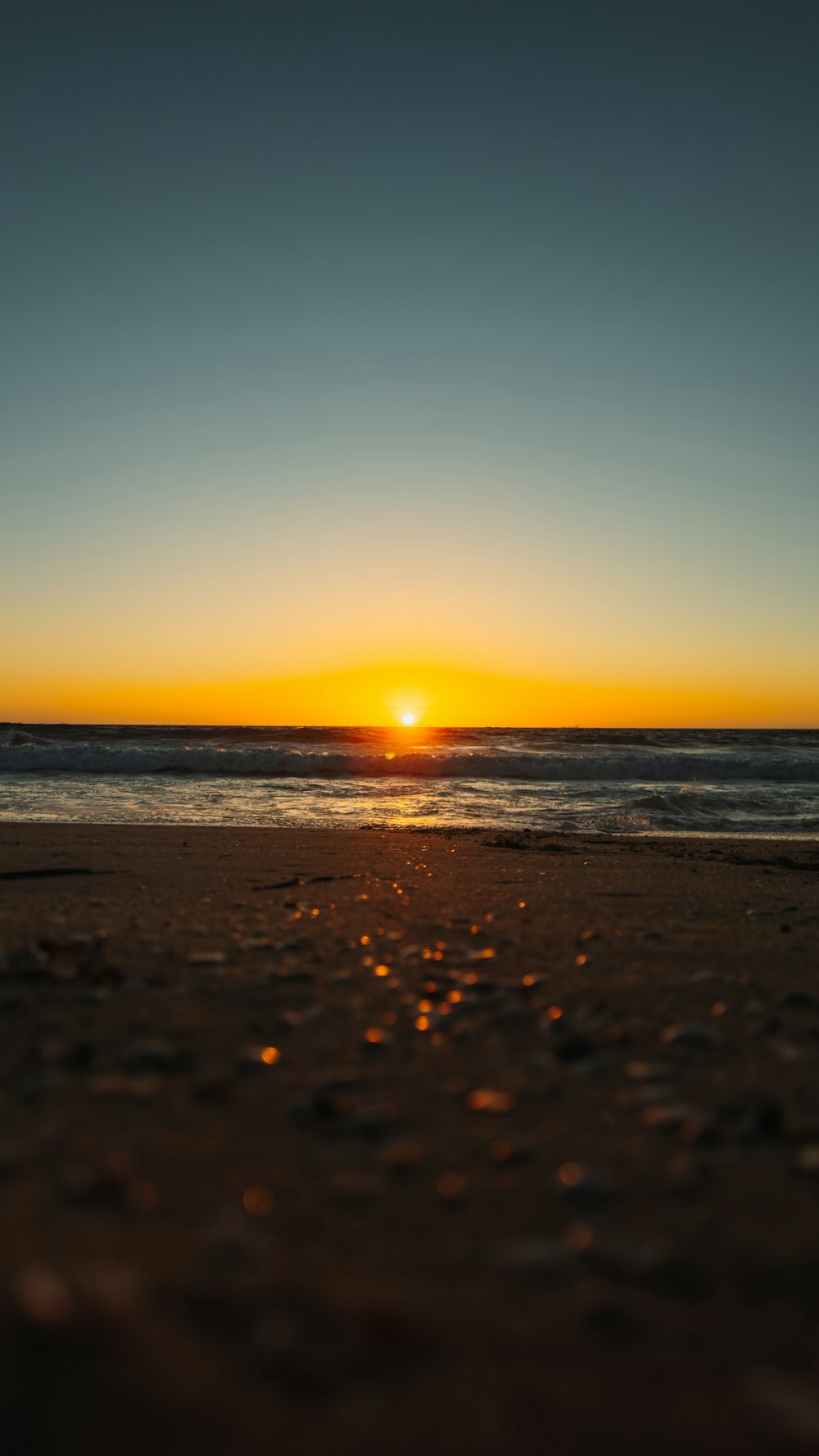 the sun is setting over the ocean on the beach