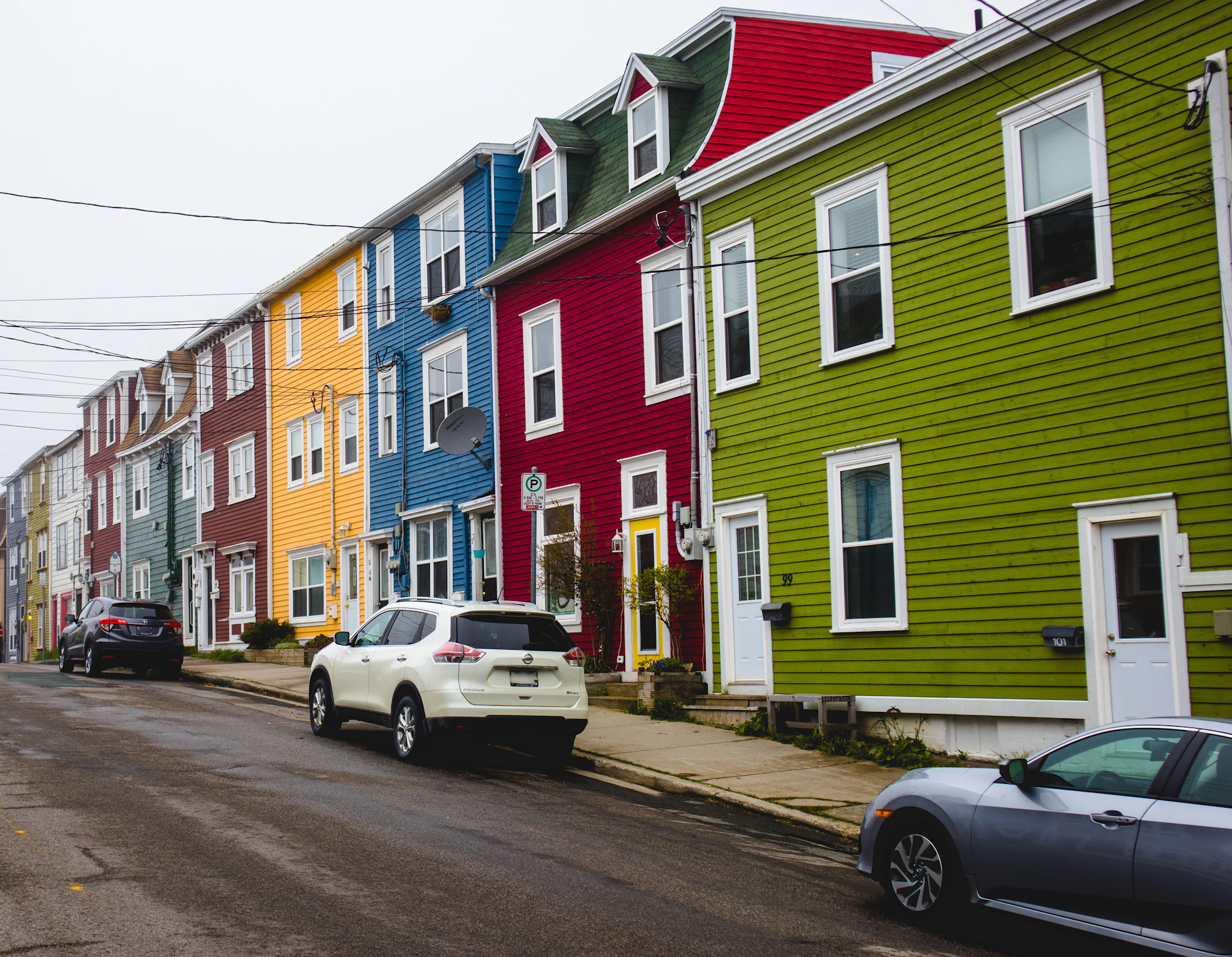 a row of houses with cars parked on the side of the street