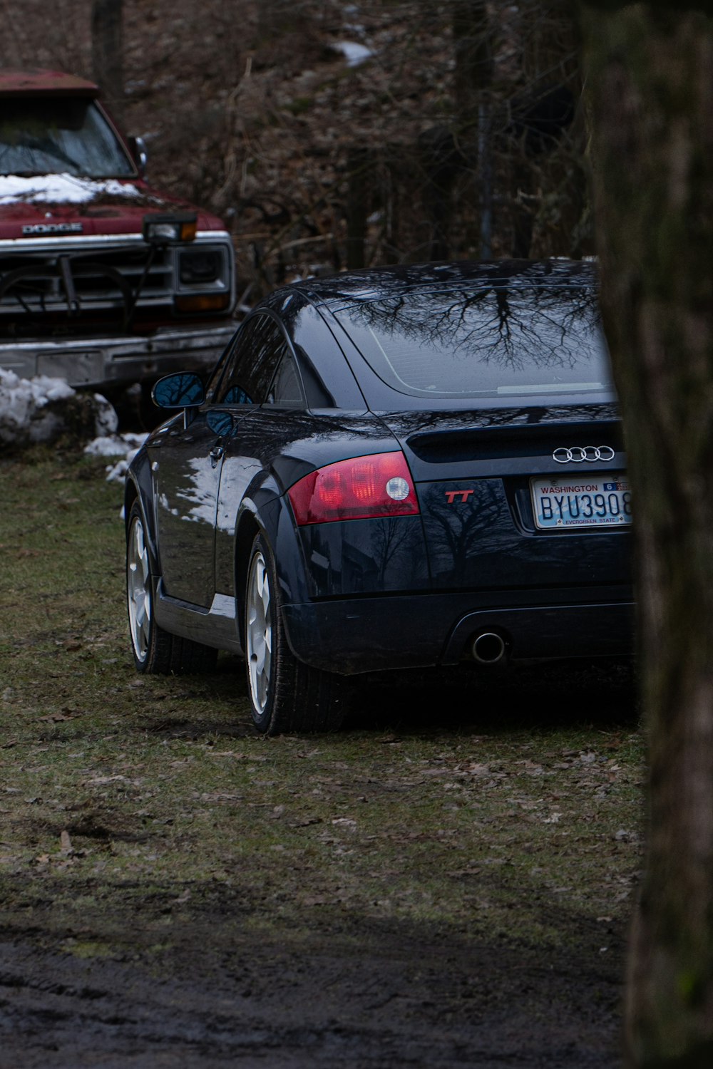 a black car parked next to a red truck