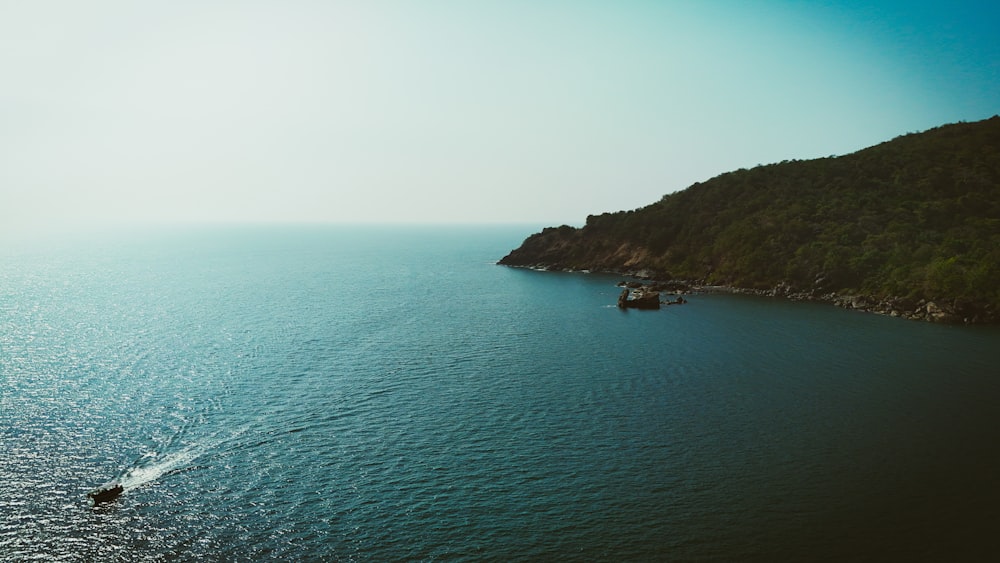 a boat is out on the water near a hill