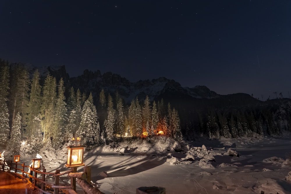 a night time scene of a snowy mountain with a cabin