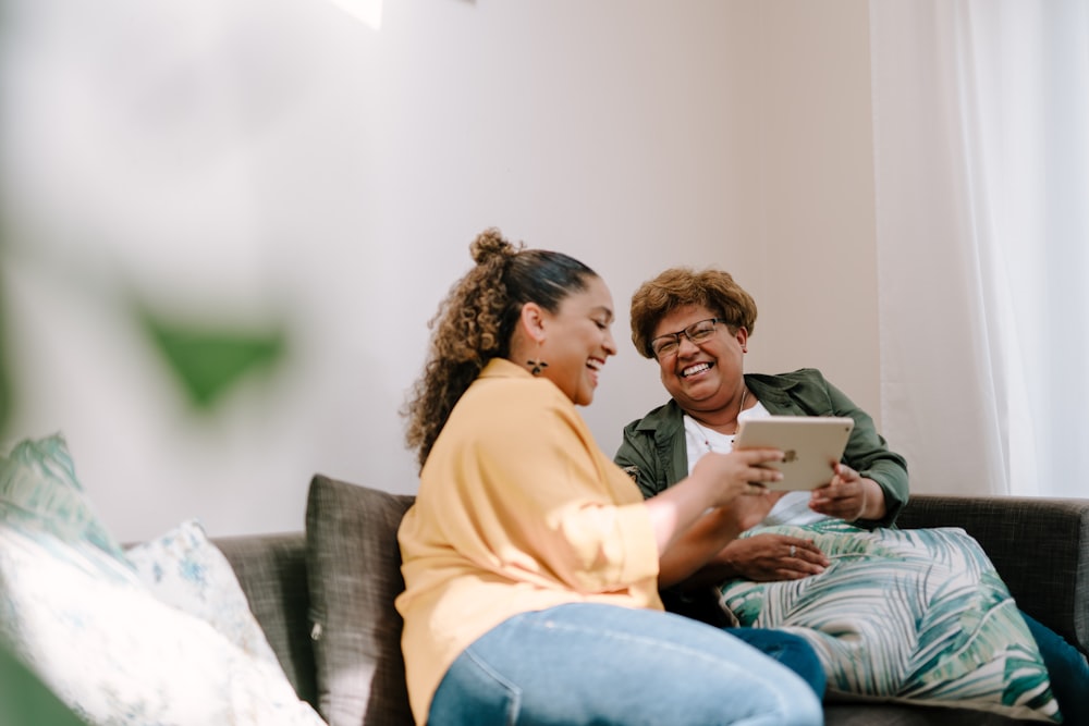 a man and woman sitting on a couch looking at a tablet