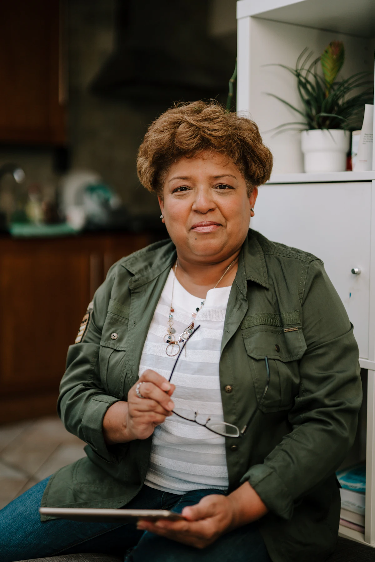 Smiling senior woman sitting outdoors, holding a tablet to join a live Valia Live session