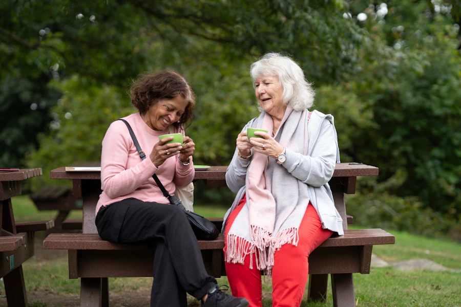 Two senior friends laughing together over tea outdoors