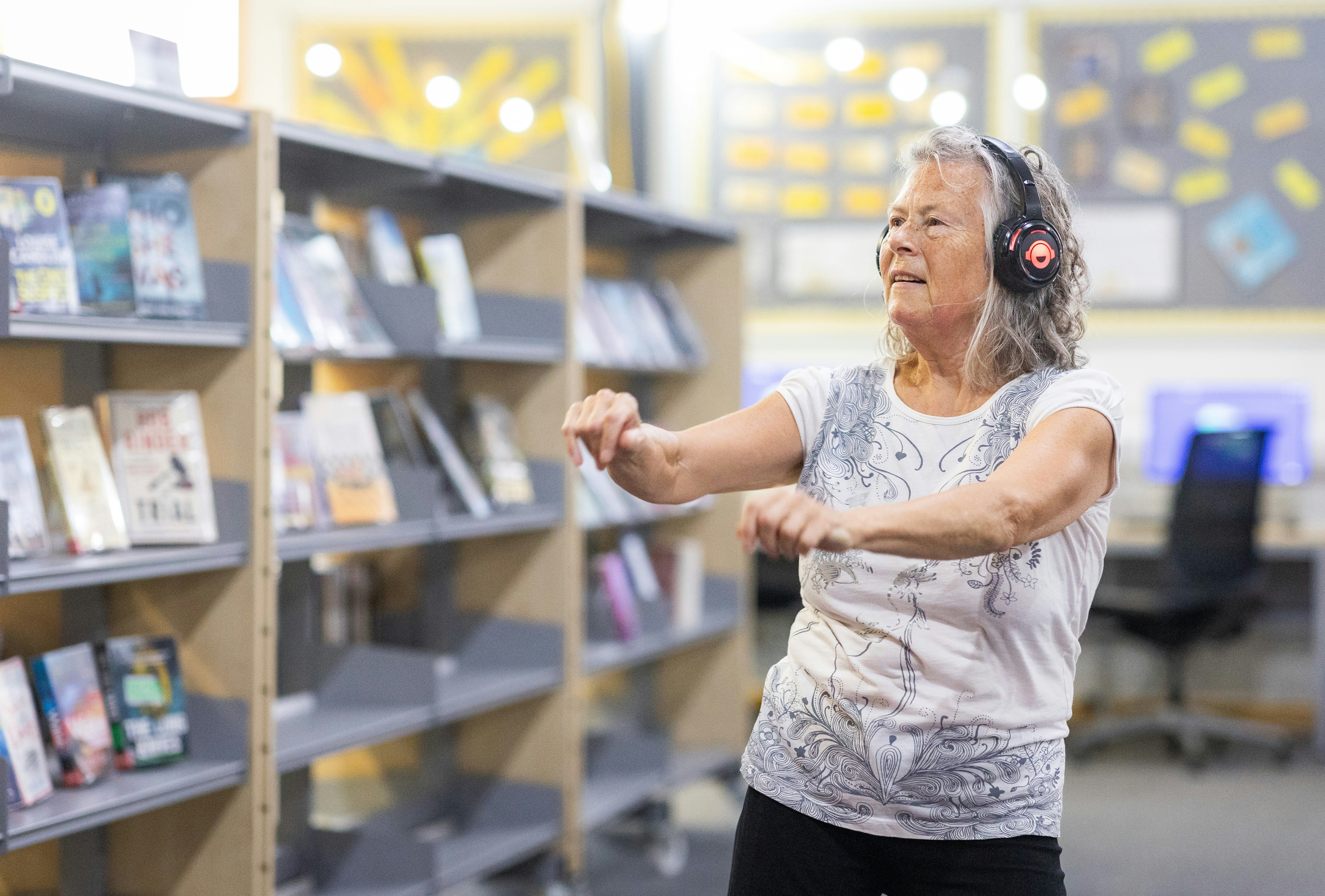 Uma mulher mais velha está ouvindo música em uma biblioteca