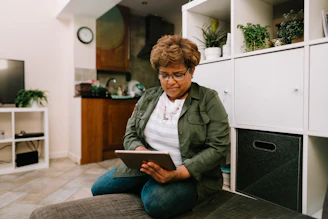 a woman sitting on the floor looking at a tablet