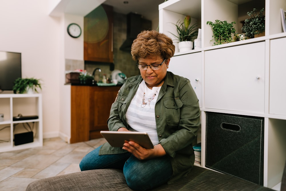 a woman sitting on the floor looking at a tablet