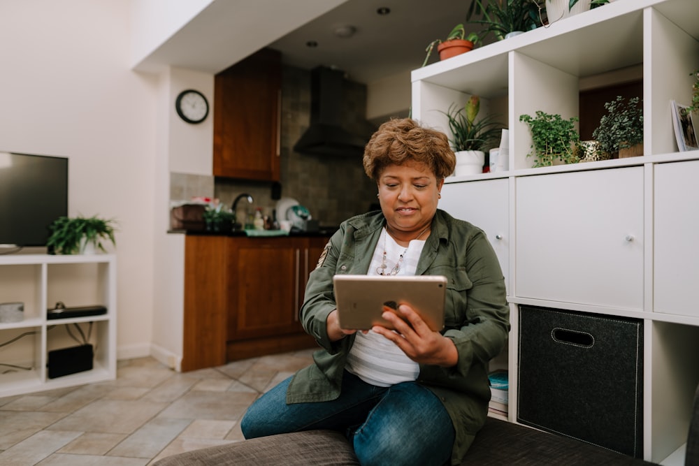 a woman sitting on the floor looking at a tablet