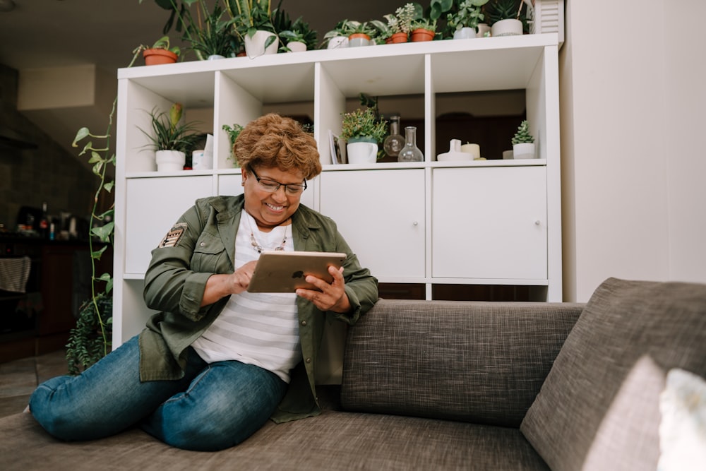 a woman sitting on a couch looking at a tablet