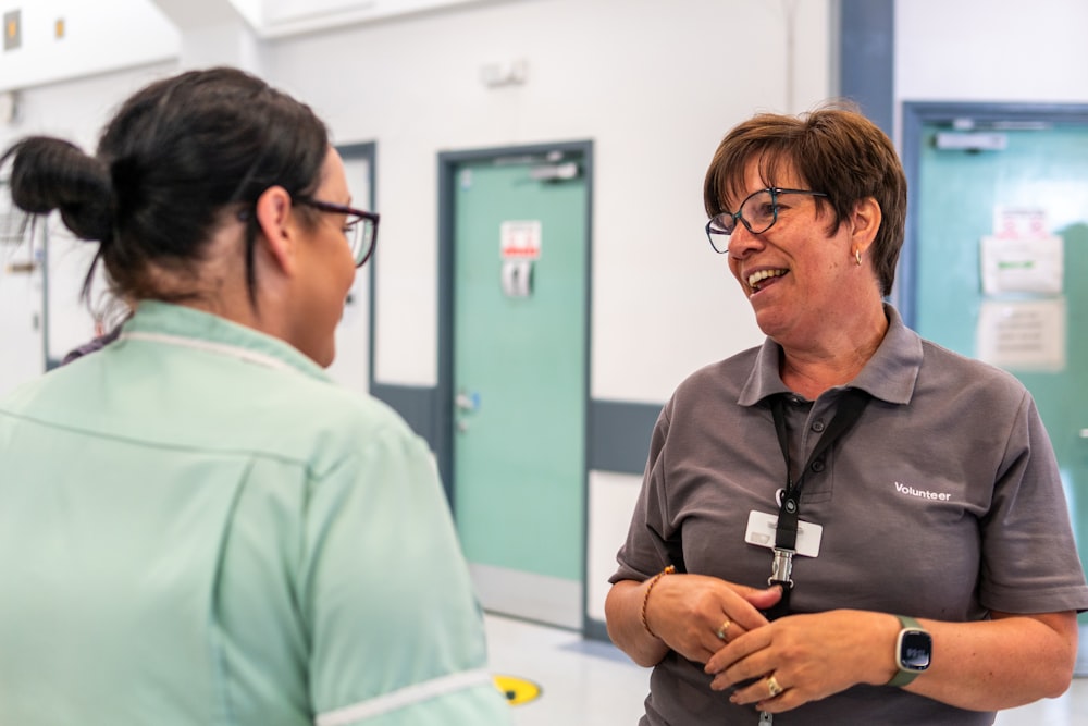 a woman talking to another woman in a hospital hallway