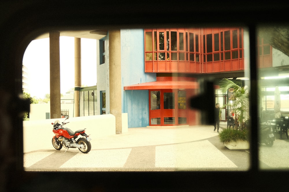 a red motorcycle parked in front of a building