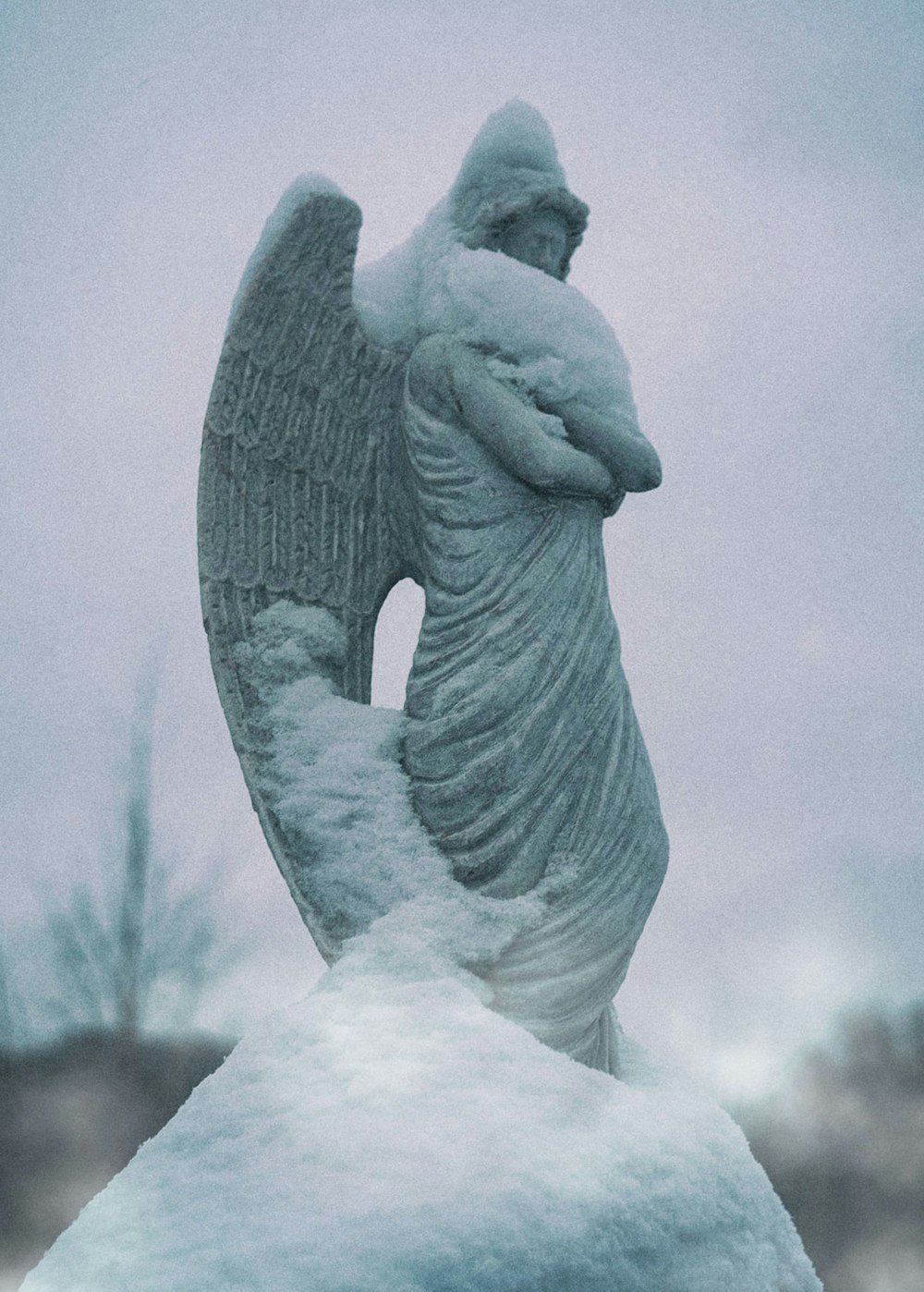 a statue of an angel is covered in snow