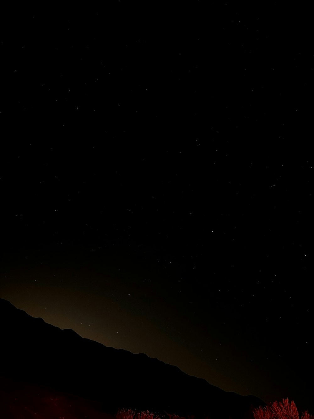 the night sky with stars above a mountain range