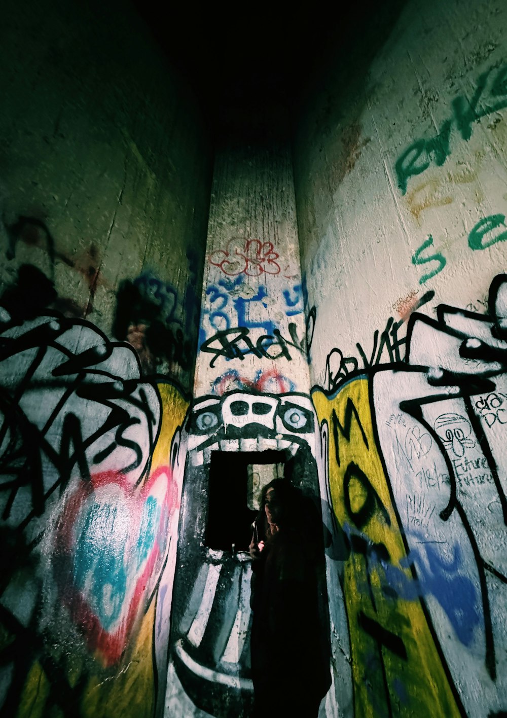 a person standing in a tunnel covered in graffiti