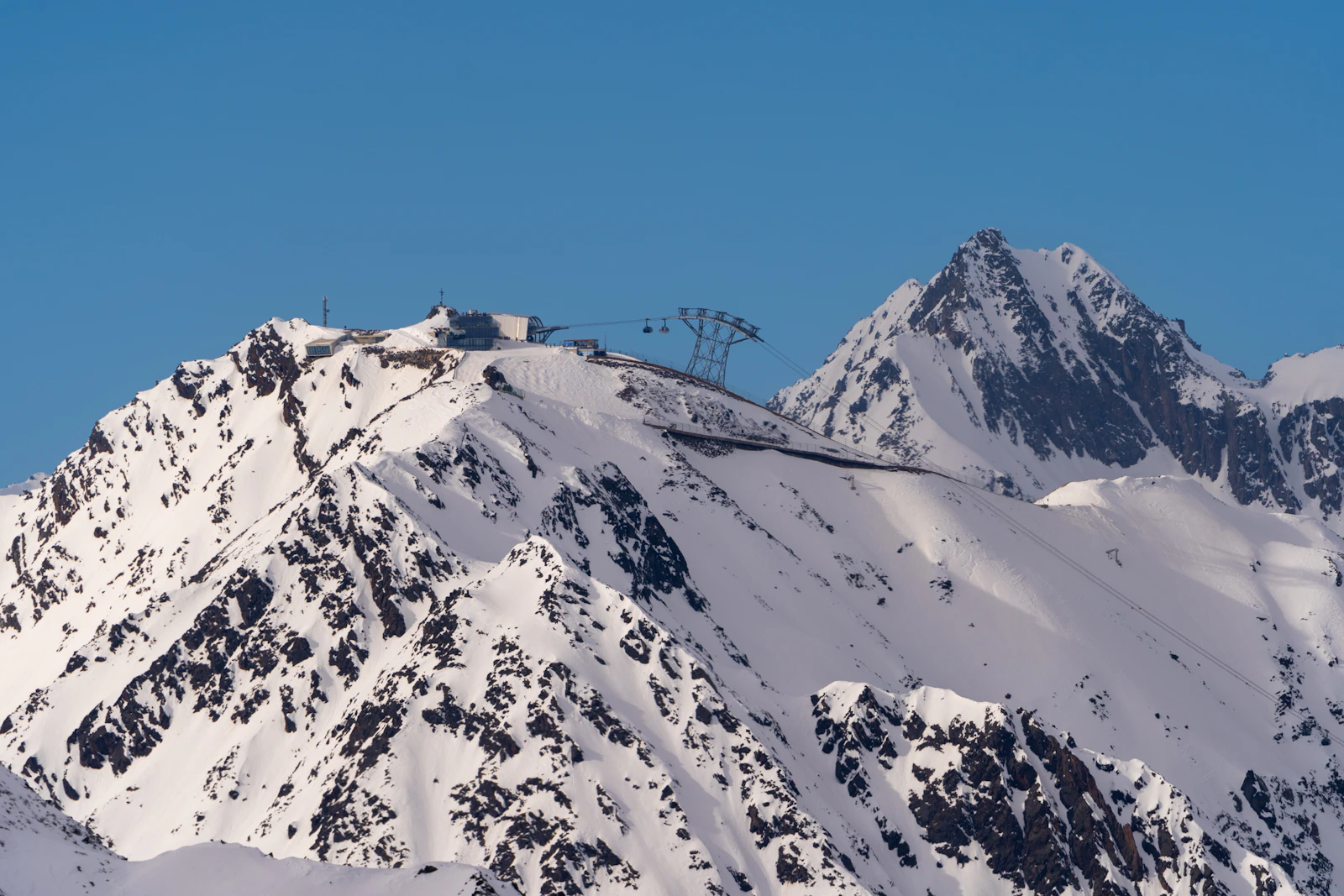 Lift infrastructure stands on a snow-covered rocky summit near Sölden.