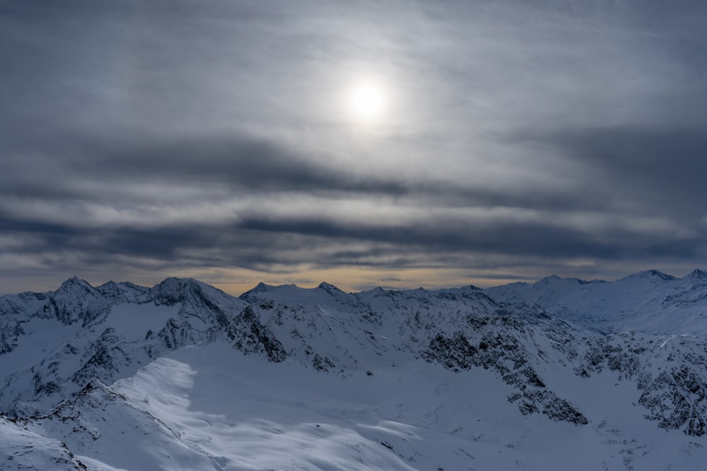 the sun is shining over a snowy mountain range