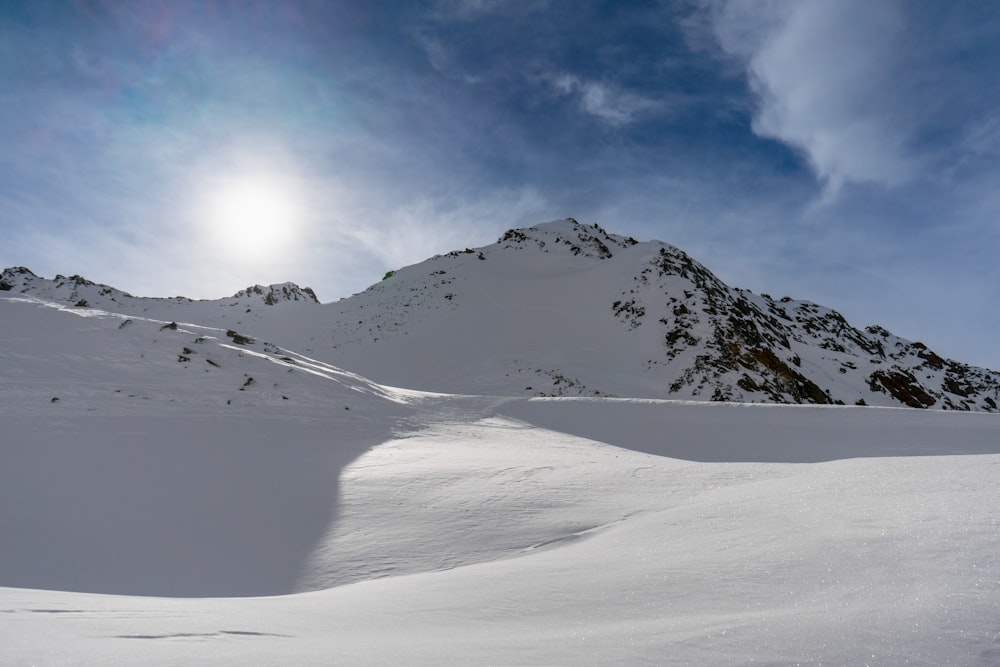 the sun is shining over a snowy mountain