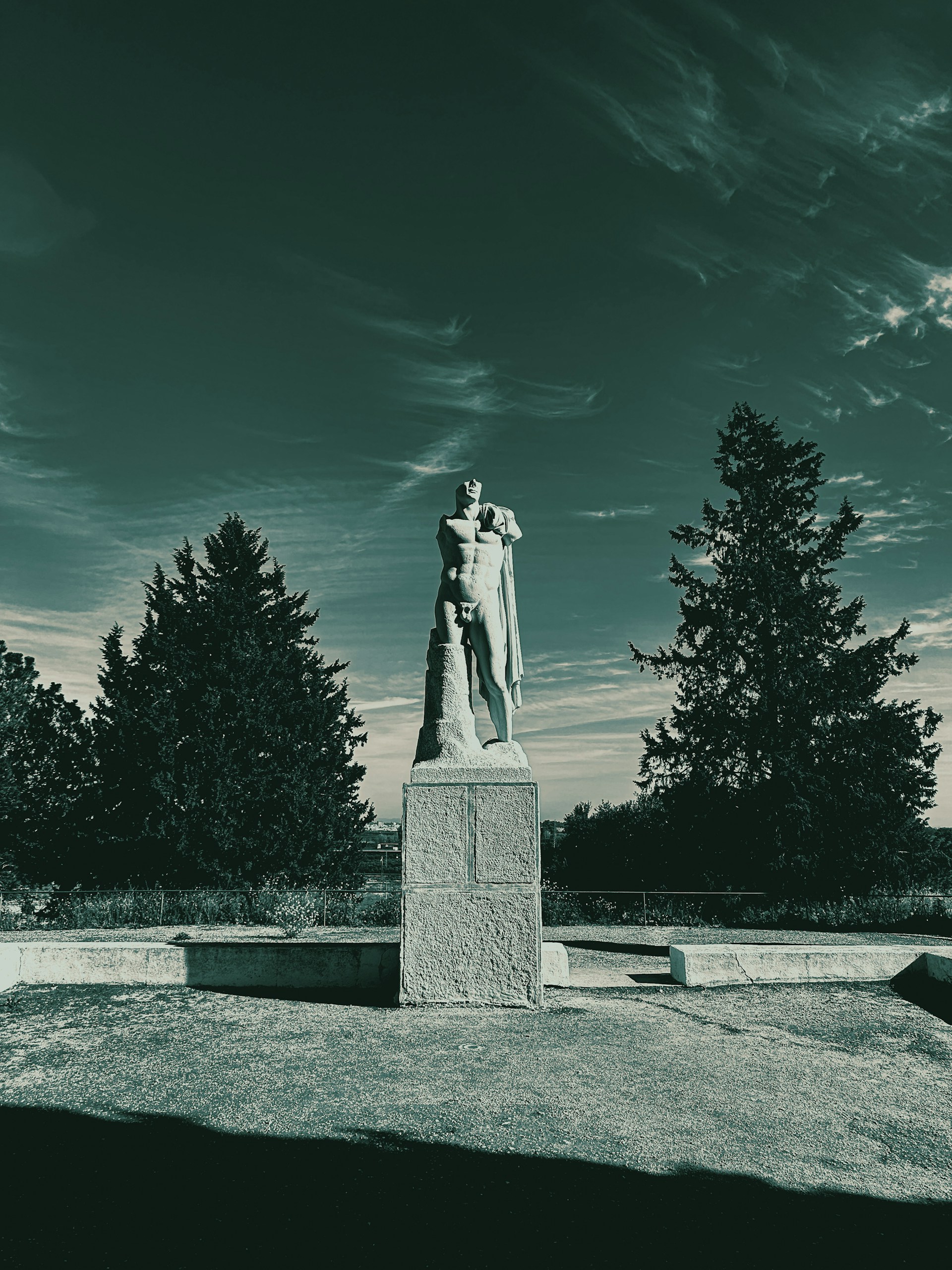 a black and white photo of a statue in a park