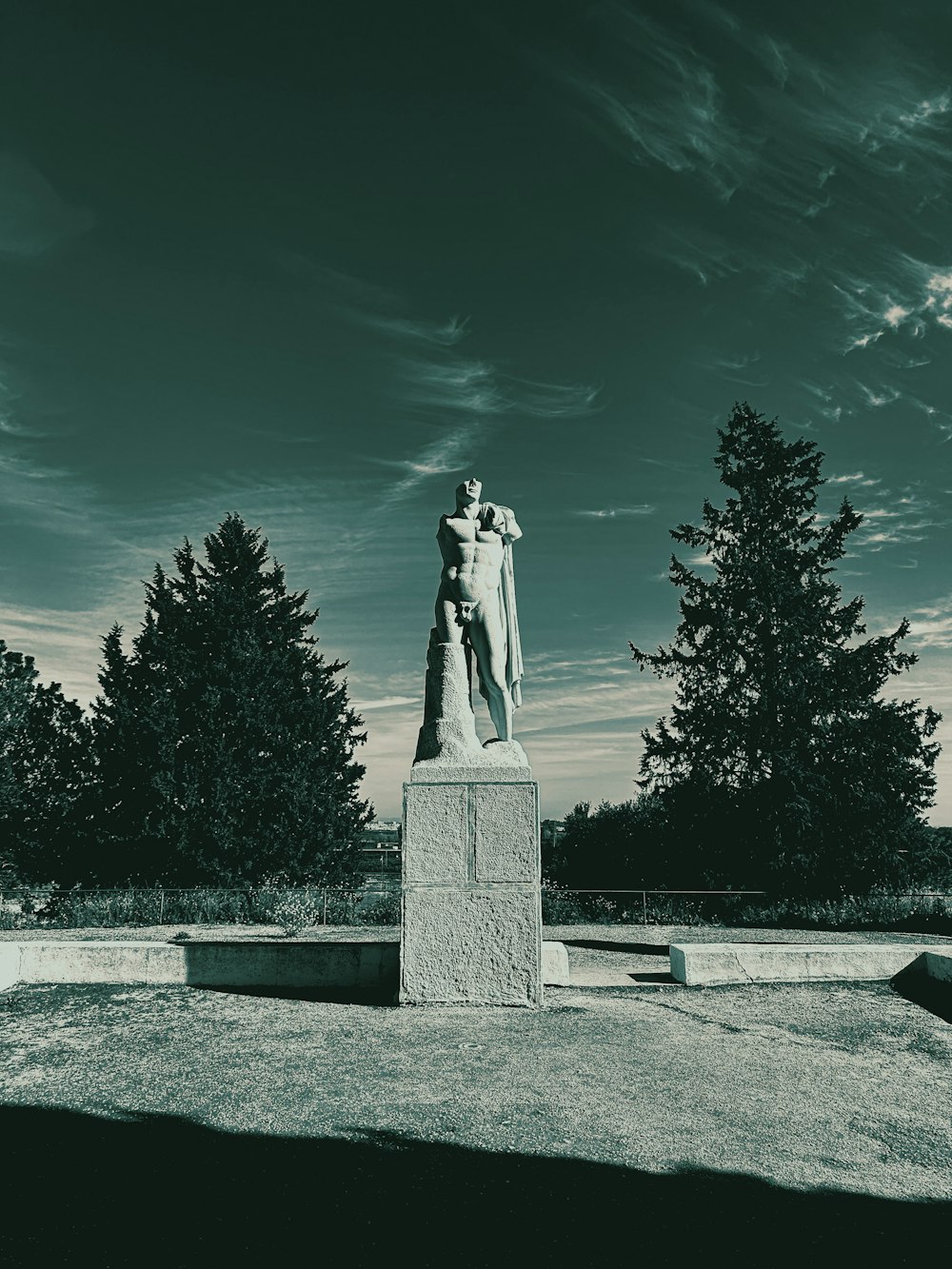 a black and white photo of a statue in a park