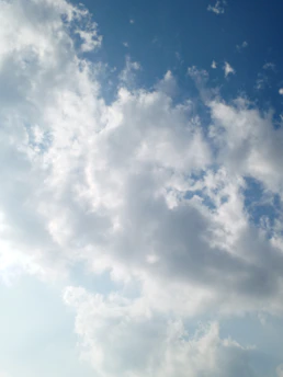a plane flying through a cloudy blue sky