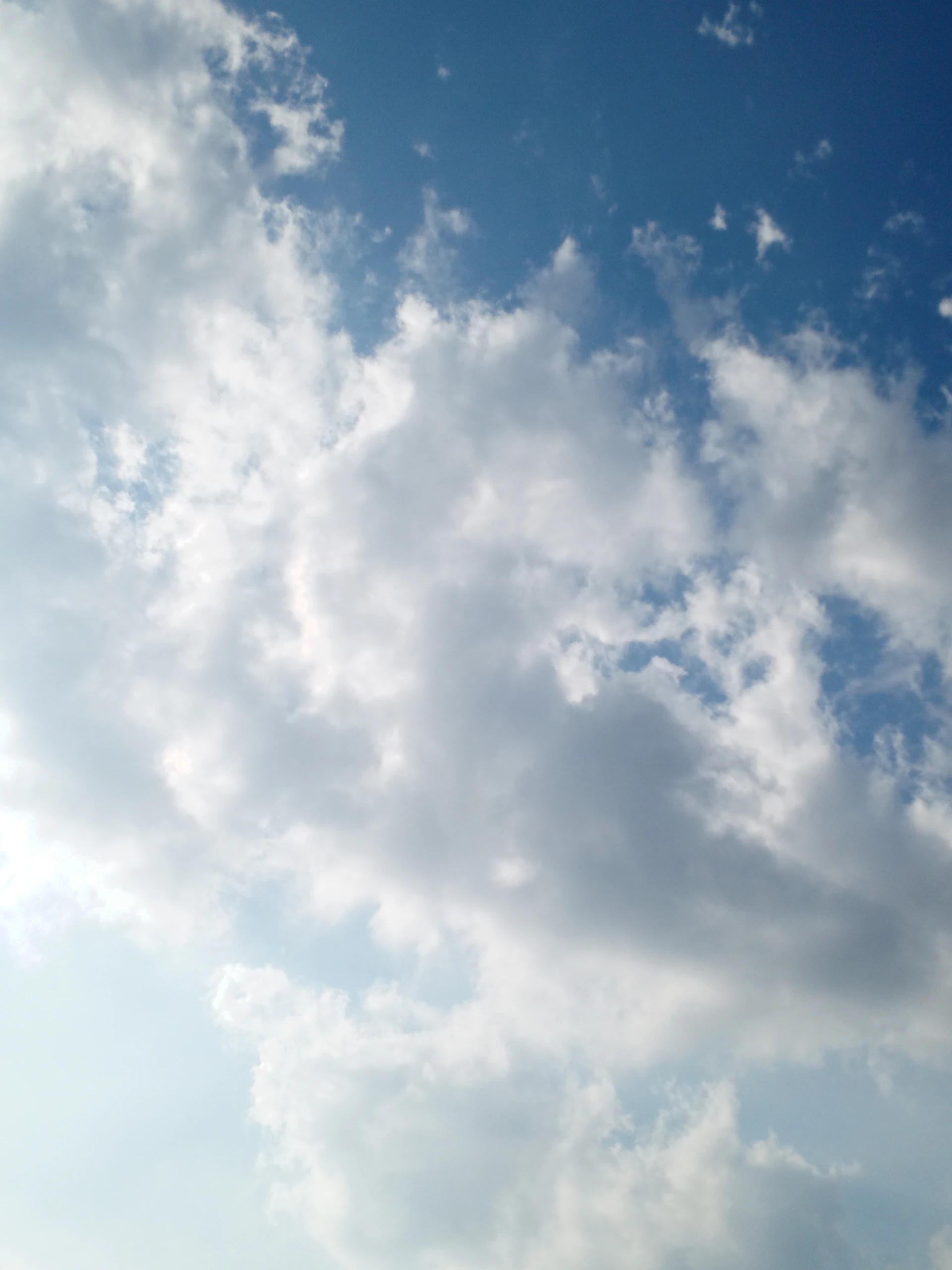 a plane flying through a cloudy blue sky