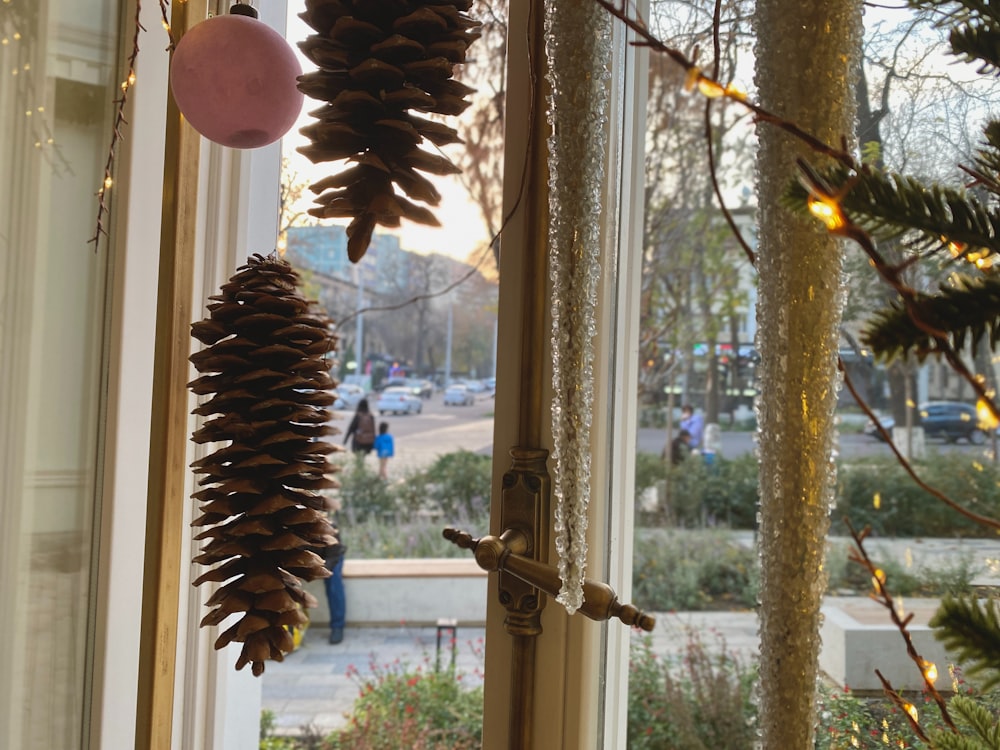 a pine cone hanging from a window next to a christmas tree