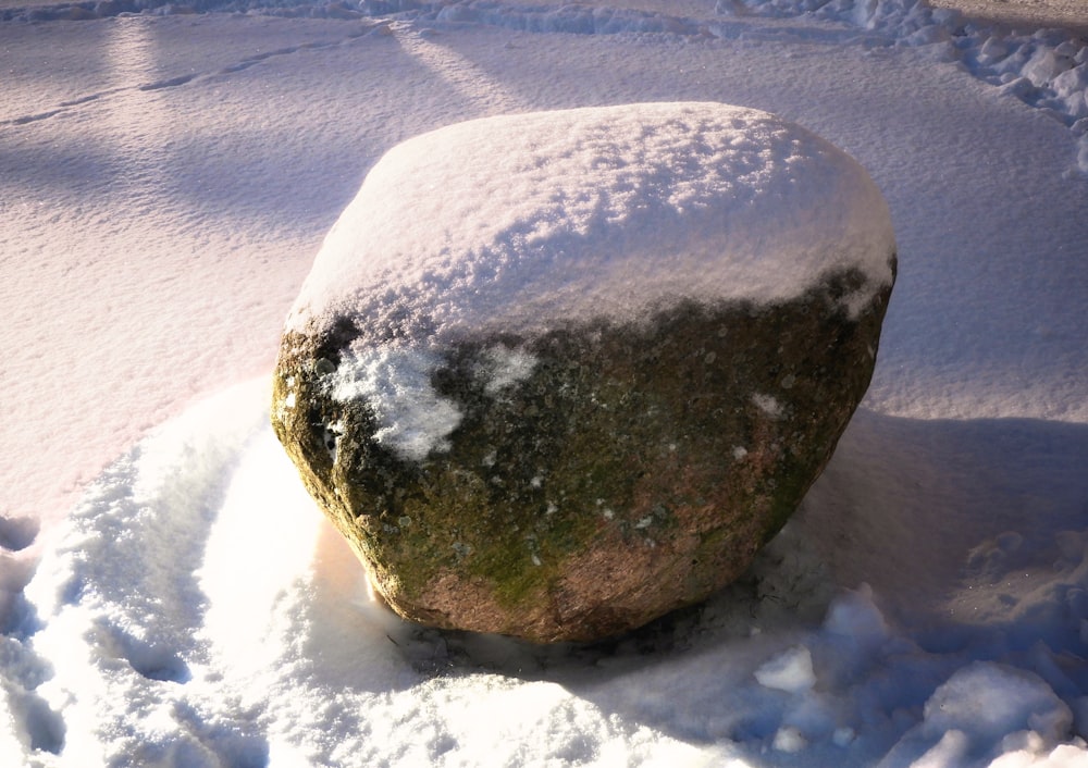 a large rock covered in snow next to a sidewalk