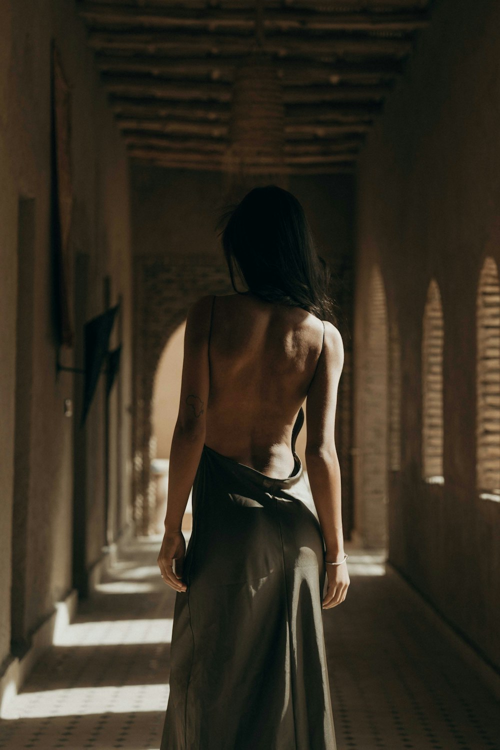 a woman in a long skirt walking down a hallway