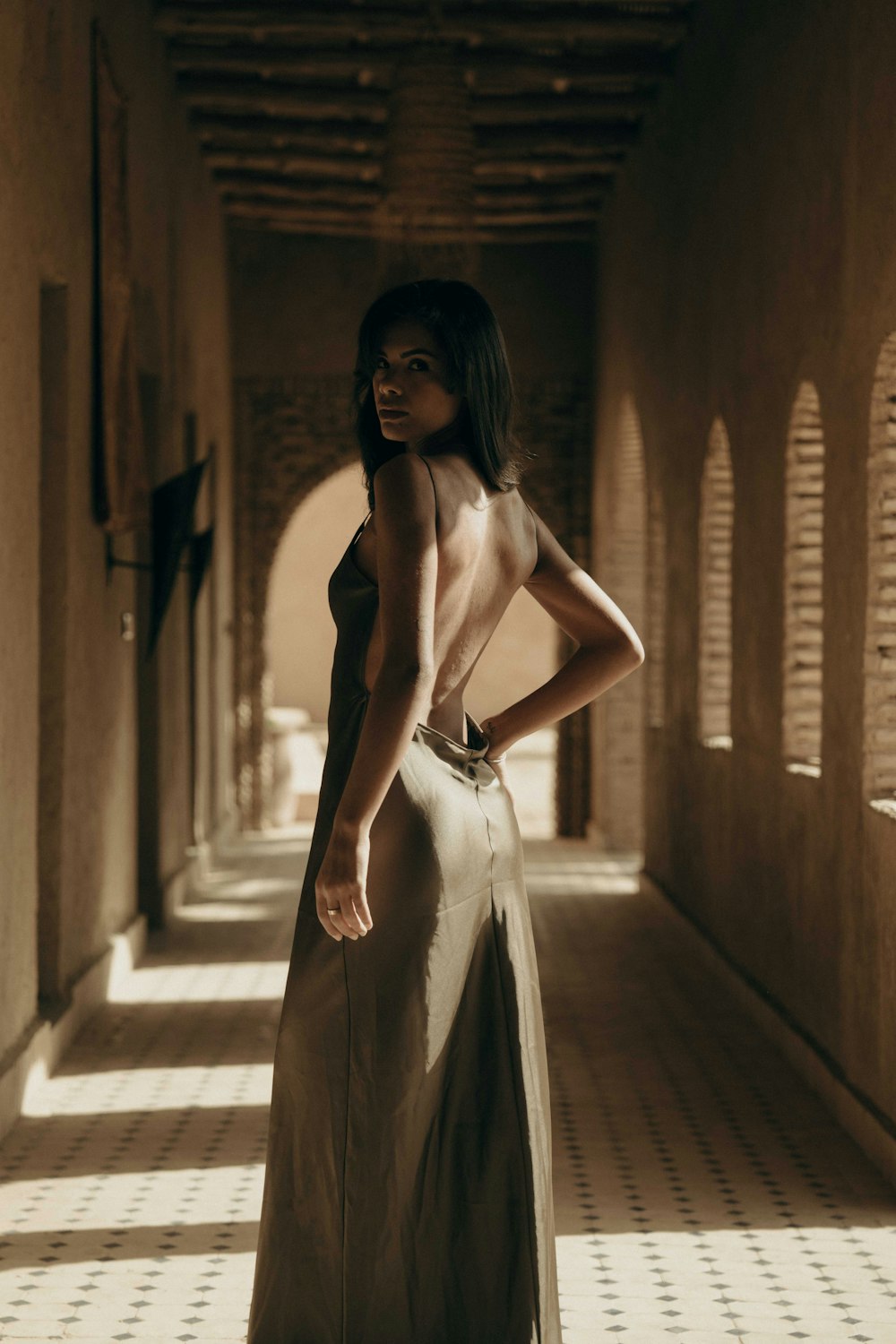 a woman in a long dress standing in a hallway