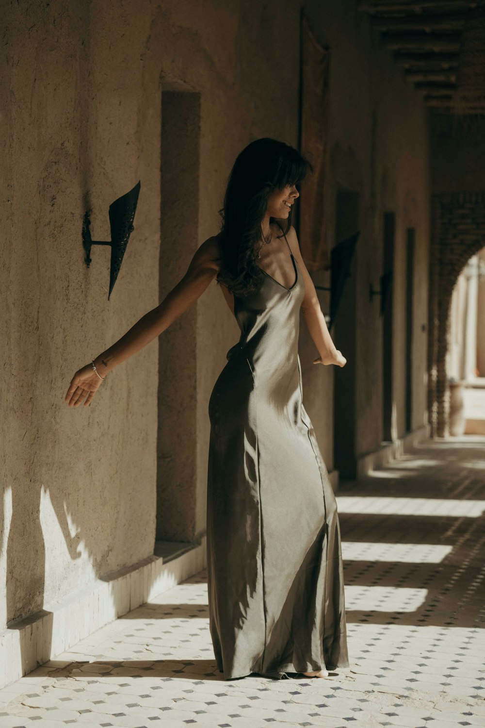 a woman in a long dress walking down a hallway