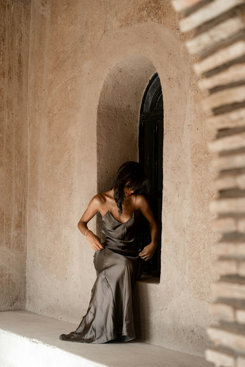 a woman leaning against a wall with her hands on her hips