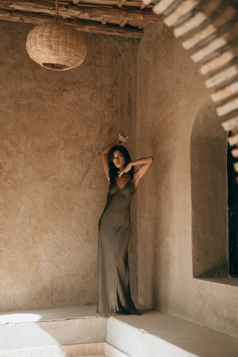 a woman in a long dress leaning against a wall