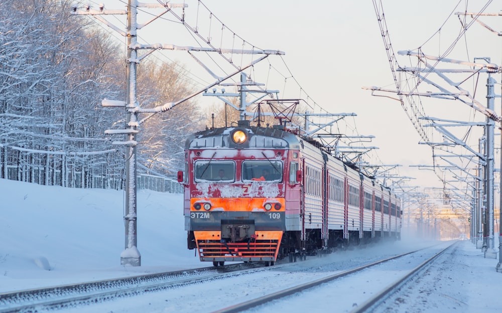 Ein Zug, der im Schnee über Bahngleise fährt