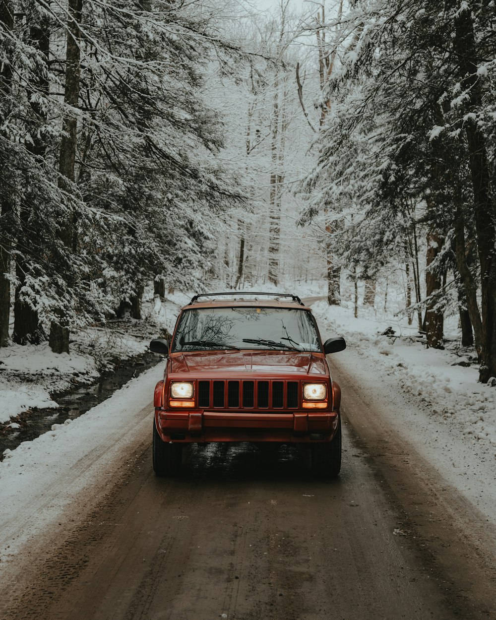 una jeep rossa che guida lungo una strada innevata