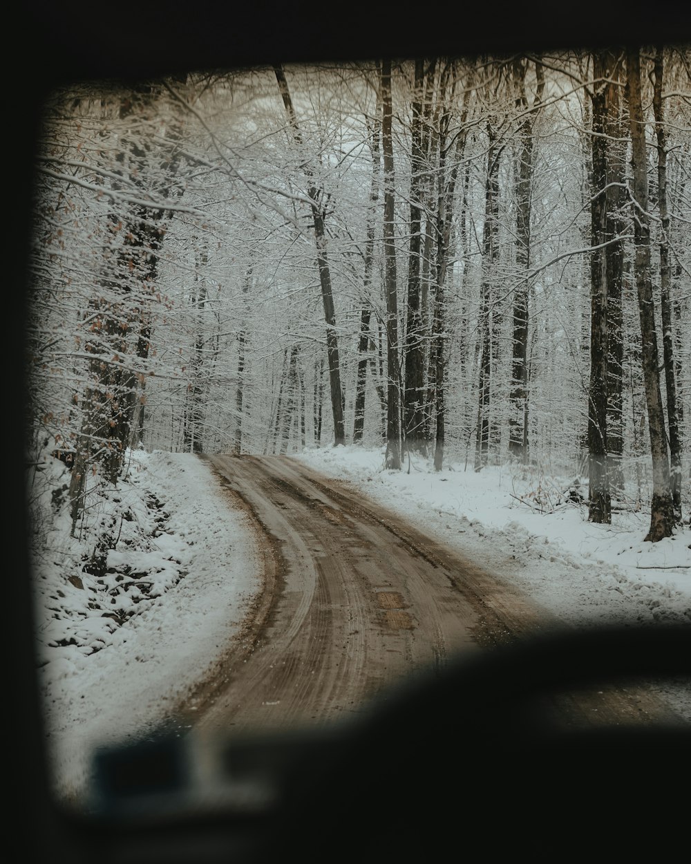 Un coche conduciendo por una carretera cubierta de nieve