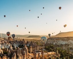 a group of hot air balloons flying over a valley