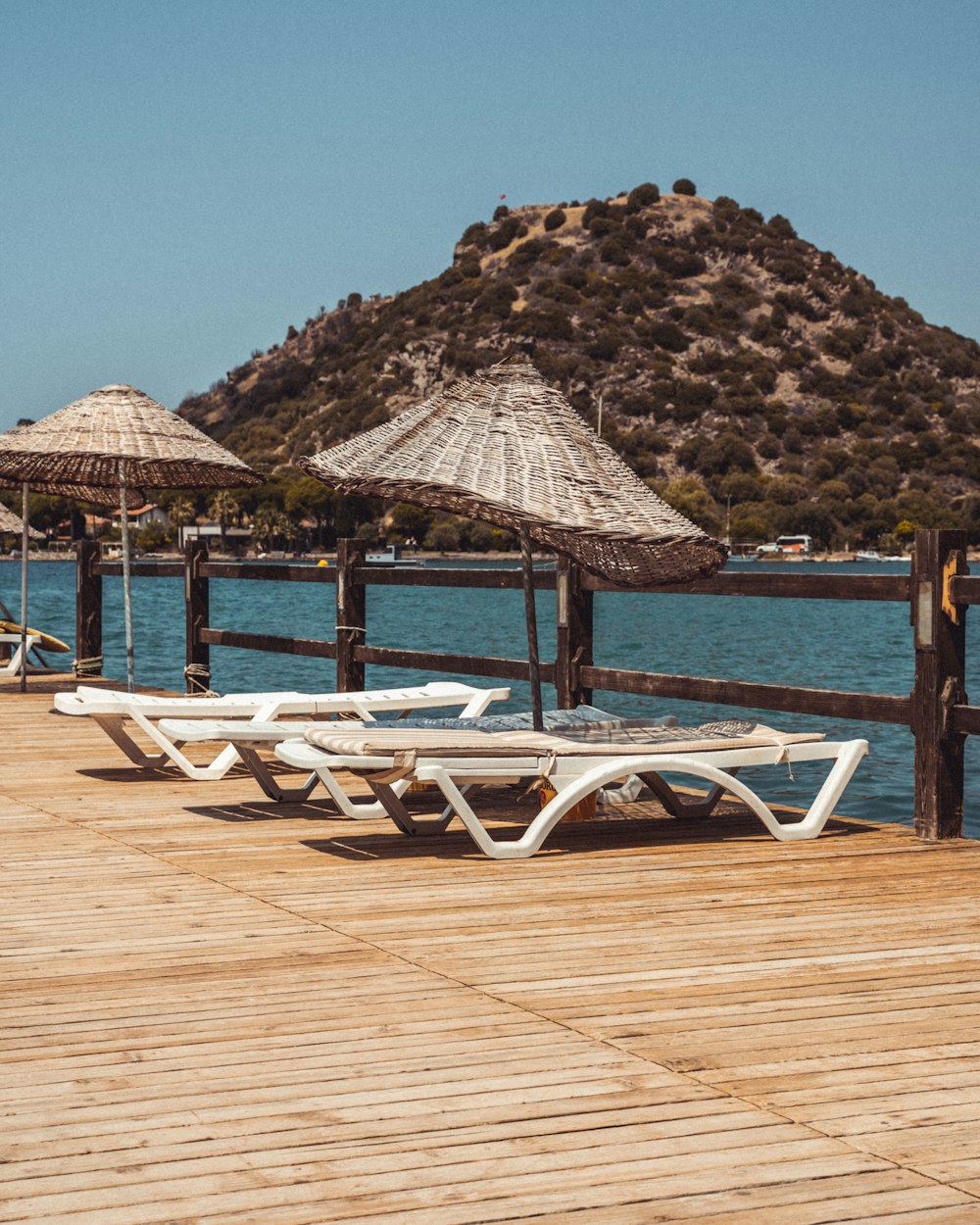 a wooden dock with chairs and umbrellas on it