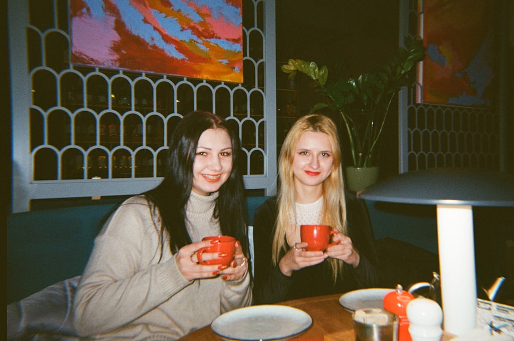 two women sitting at a table holding red cups