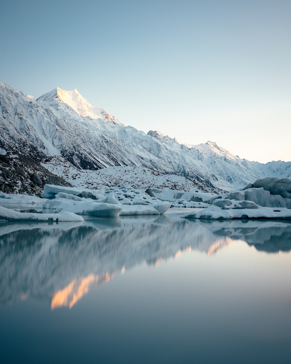 a snow covered mountain with a lake in front of it