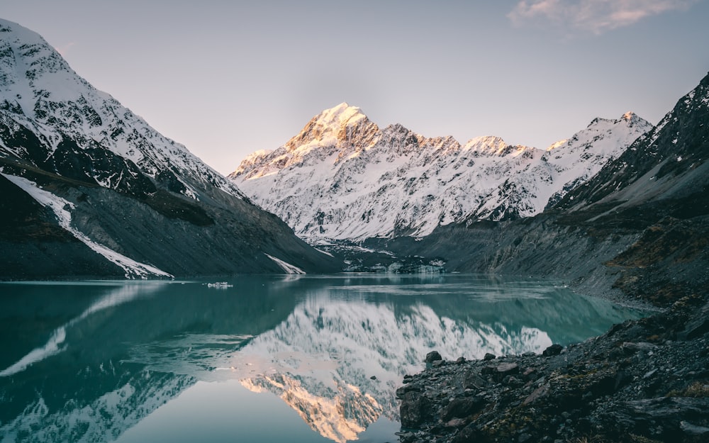 a mountain range is reflected in the still water of a lake