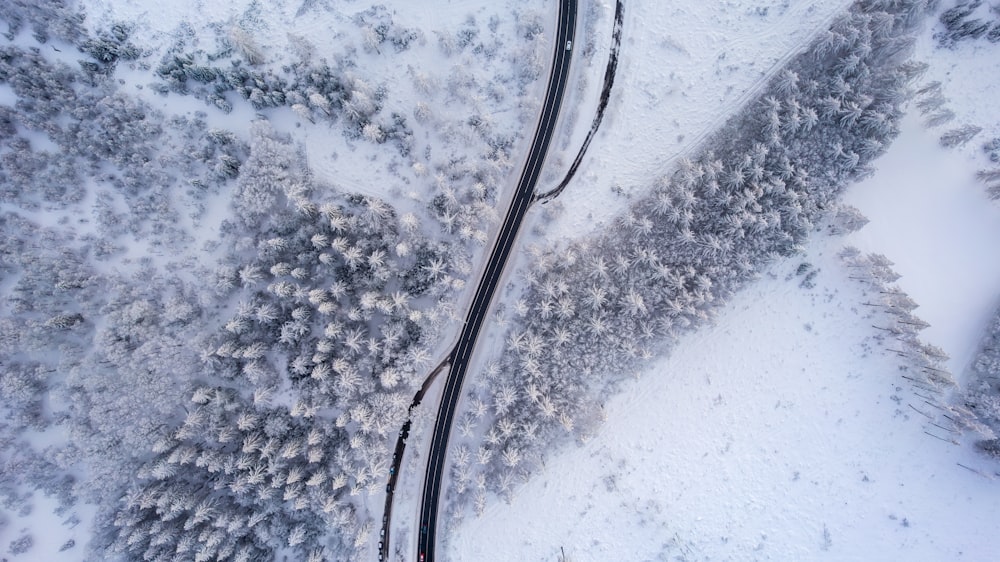 an aerial view of a road in the middle of a snow covered forest