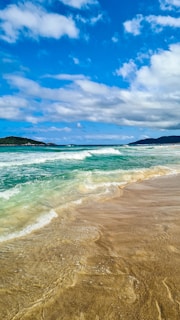 a sandy beach with waves coming in to shore