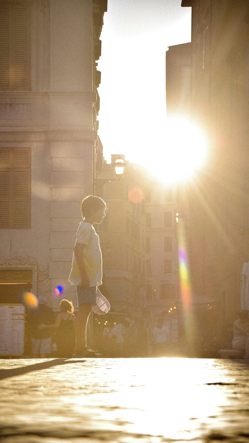 a young boy walking down a street next to tall buildings