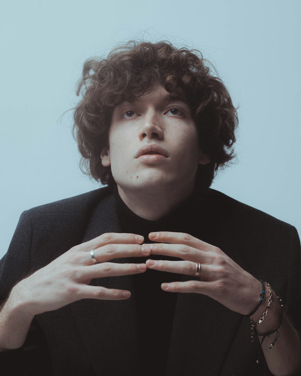 a young man with curly hair wearing a black jacket