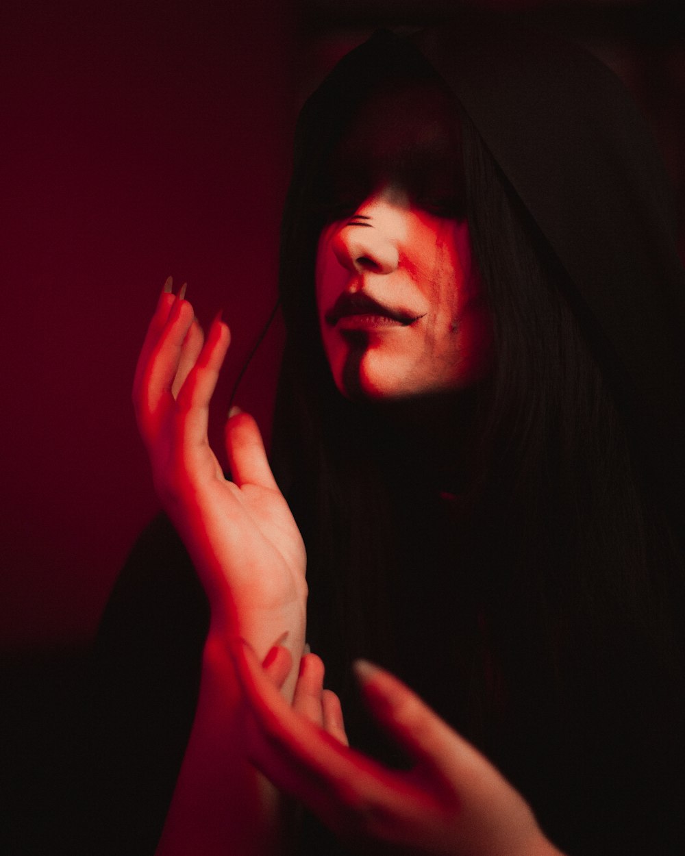 a woman in a dark room with her hands on her face